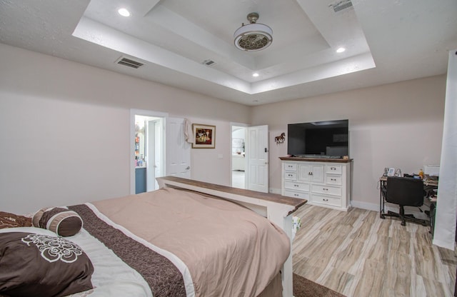 bedroom featuring a tray ceiling and light hardwood / wood-style flooring