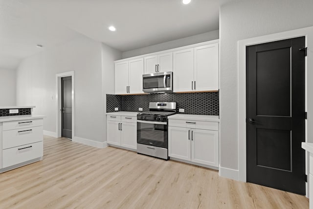 kitchen featuring tasteful backsplash, light hardwood / wood-style flooring, white cabinets, and appliances with stainless steel finishes