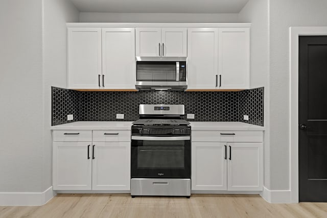 kitchen with decorative backsplash, white cabinetry, and appliances with stainless steel finishes