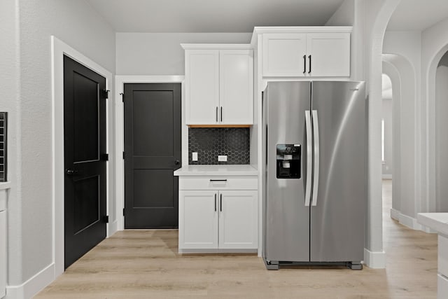 kitchen featuring white cabinets, light hardwood / wood-style floors, stainless steel refrigerator with ice dispenser, and tasteful backsplash