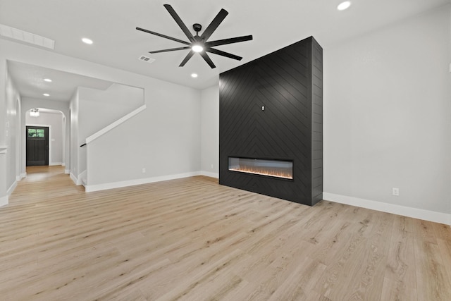 unfurnished living room featuring a fireplace, light hardwood / wood-style flooring, and ceiling fan