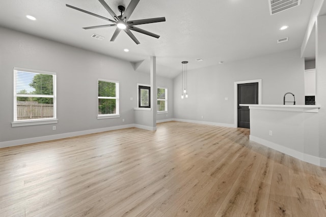 unfurnished living room featuring ceiling fan, light hardwood / wood-style flooring, vaulted ceiling, and sink