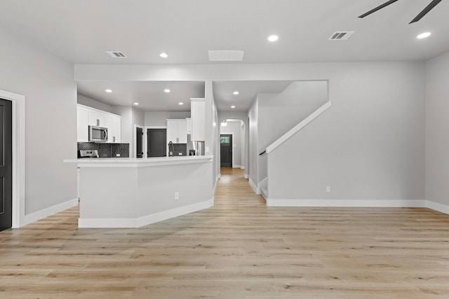 kitchen featuring white cabinets, ceiling fan, tasteful backsplash, and light hardwood / wood-style flooring