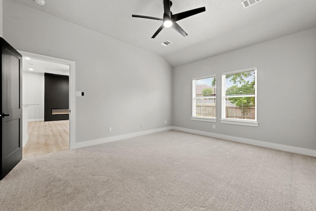 empty room featuring light carpet, vaulted ceiling, and ceiling fan