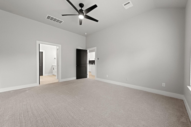 unfurnished bedroom featuring ensuite bath, ceiling fan, light colored carpet, and vaulted ceiling