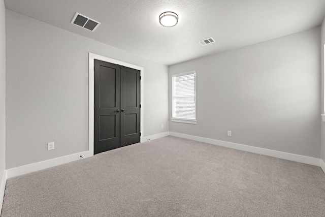 unfurnished bedroom with carpet, a textured ceiling, and a closet