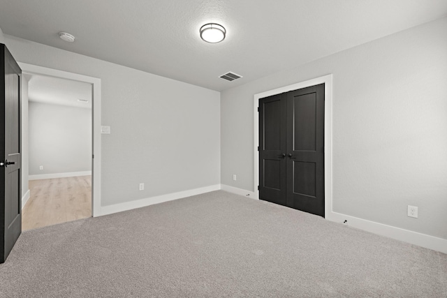 unfurnished bedroom featuring a closet and light colored carpet