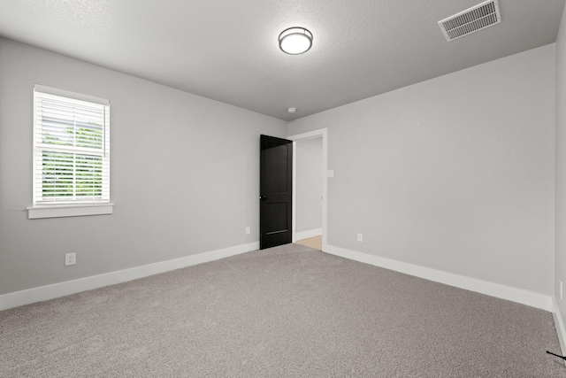 carpeted empty room featuring a textured ceiling