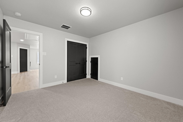 unfurnished bedroom with a closet, light colored carpet, and a textured ceiling