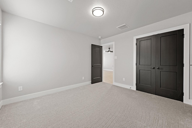 unfurnished bedroom featuring a textured ceiling, carpet floors, and a closet