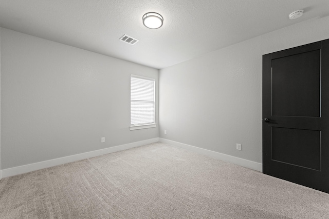 carpeted empty room with a textured ceiling