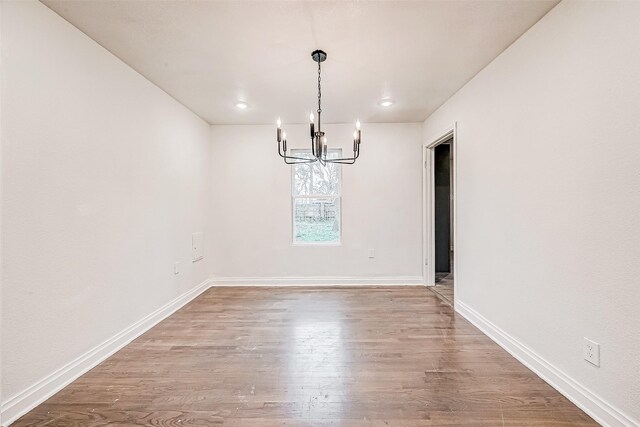 unfurnished dining area featuring hardwood / wood-style floors and a chandelier