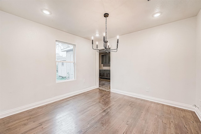 unfurnished dining area with a chandelier and hardwood / wood-style floors