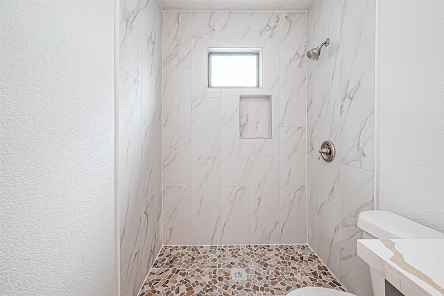 bathroom with toilet and tiled shower