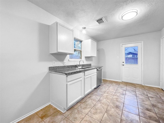 kitchen featuring white cabinets, sink, stainless steel dishwasher, a textured ceiling, and light tile patterned flooring