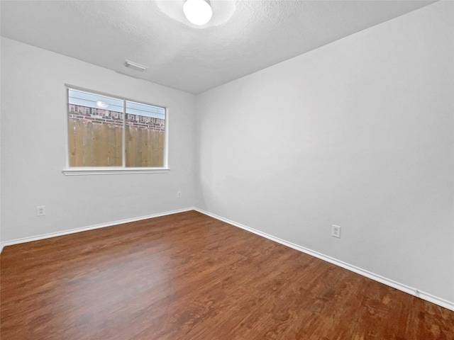 empty room featuring dark hardwood / wood-style floors and a textured ceiling