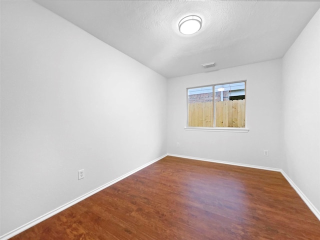 spare room featuring hardwood / wood-style flooring and a textured ceiling