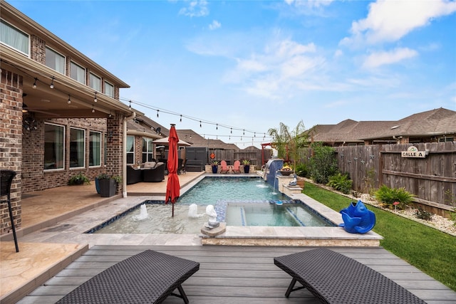 view of pool with an in ground hot tub, pool water feature, and a wooden deck