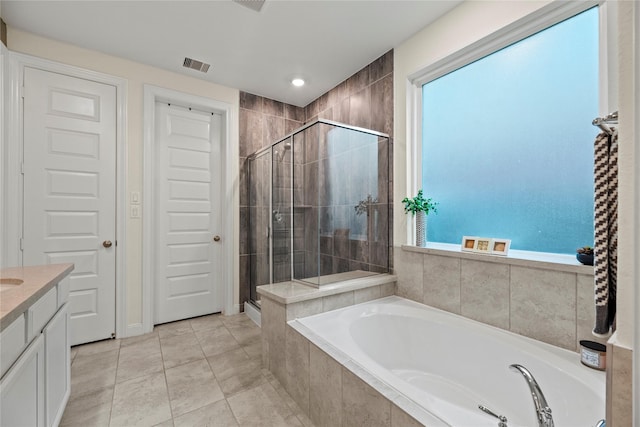 bathroom with plus walk in shower, vanity, a wealth of natural light, and tile patterned flooring