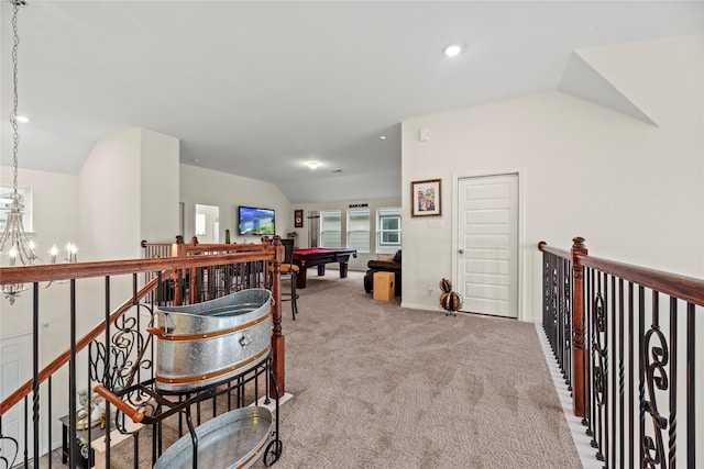 corridor featuring a chandelier, light carpet, and lofted ceiling