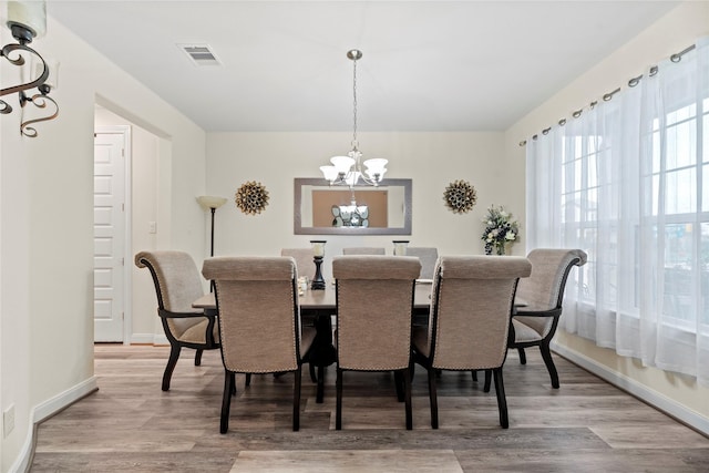 dining area with light hardwood / wood-style floors and an inviting chandelier