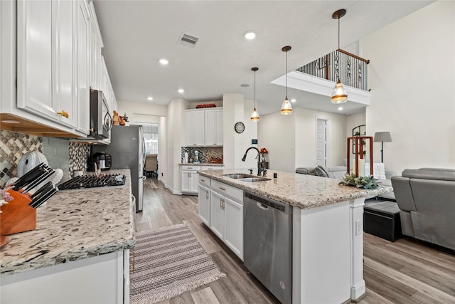 kitchen with white cabinetry, sink, an island with sink, pendant lighting, and appliances with stainless steel finishes