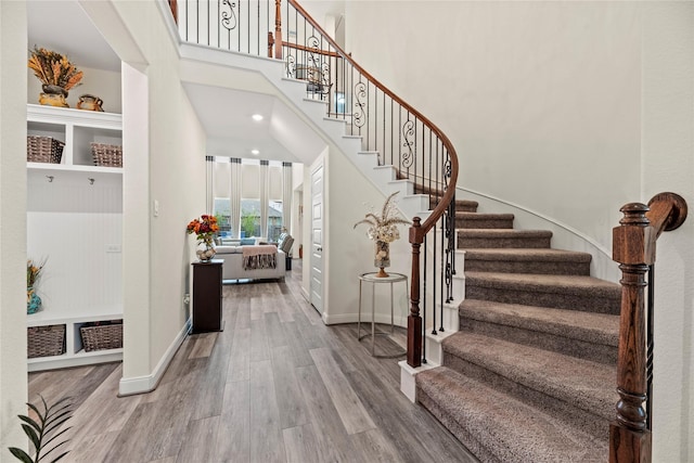 entrance foyer with wood-type flooring and a towering ceiling