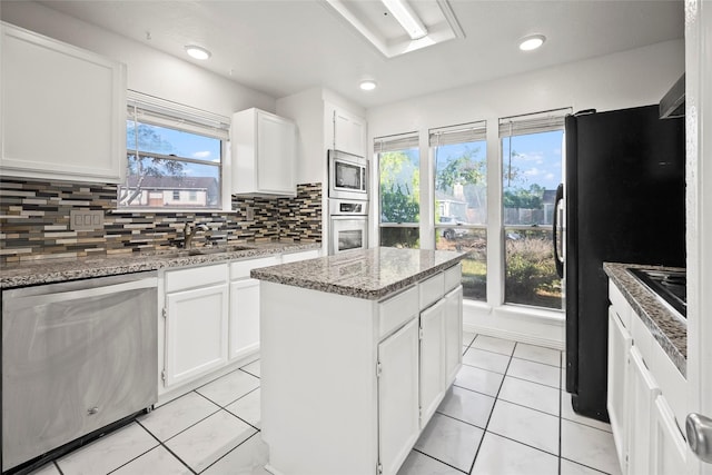 kitchen with sink, stainless steel appliances, a kitchen island, decorative backsplash, and white cabinets