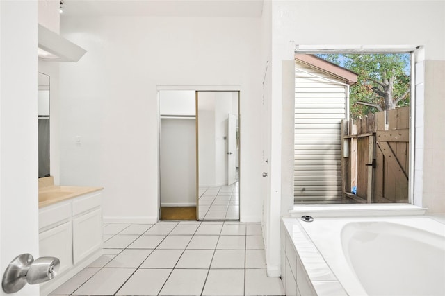 bathroom with tile patterned flooring, vanity, and tiled tub