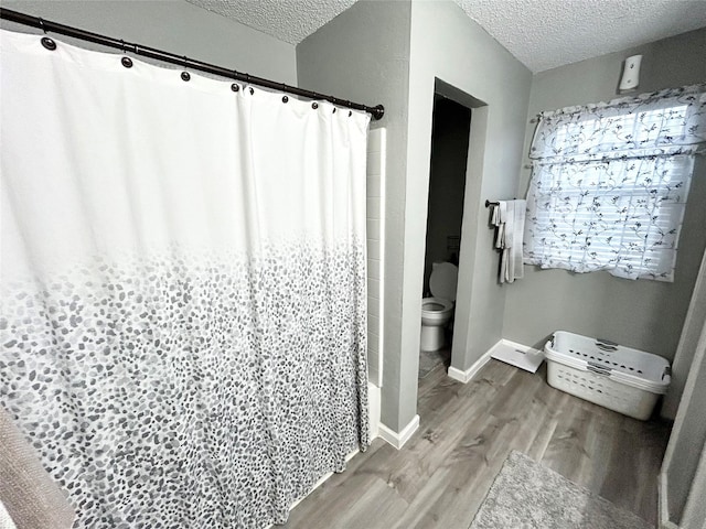 bathroom featuring independent shower and bath, wood-type flooring, a textured ceiling, and toilet