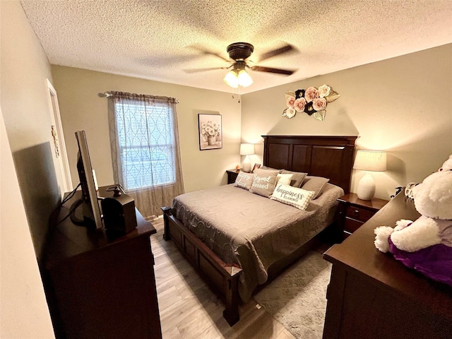 bedroom with ceiling fan, light hardwood / wood-style floors, and a textured ceiling