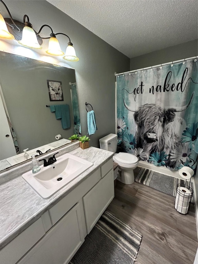 bathroom with vanity, hardwood / wood-style flooring, toilet, a textured ceiling, and curtained shower