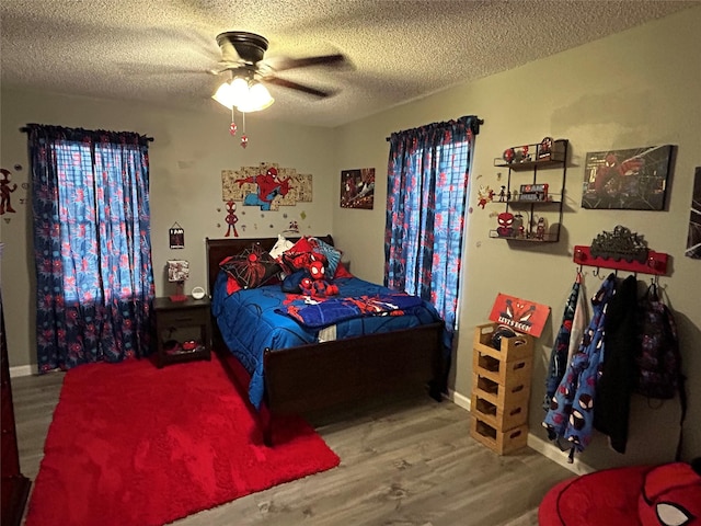 bedroom with ceiling fan, wood-type flooring, and a textured ceiling