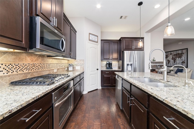 kitchen with hanging light fixtures, dark brown cabinets, stainless steel appliances, dark hardwood / wood-style floors, and decorative backsplash