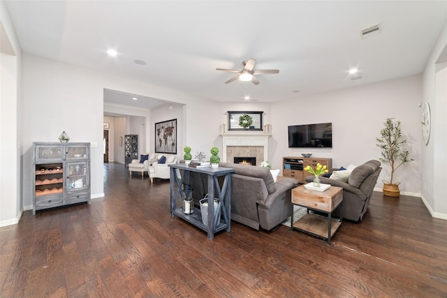 living room featuring a tile fireplace, dark hardwood / wood-style floors, and ceiling fan