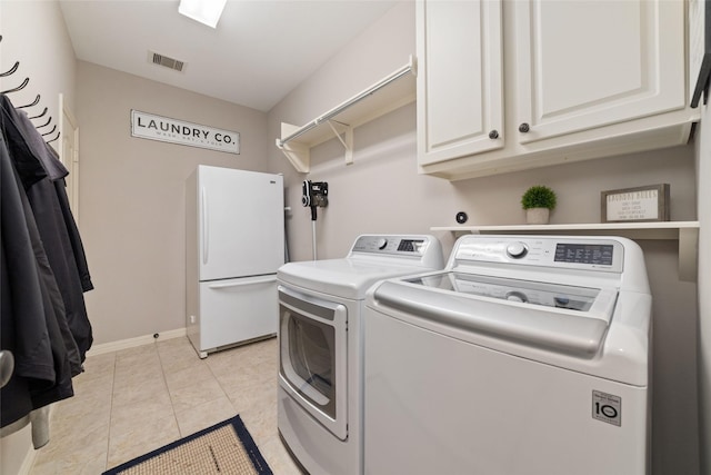 washroom with light tile patterned flooring, cabinets, and washer and dryer