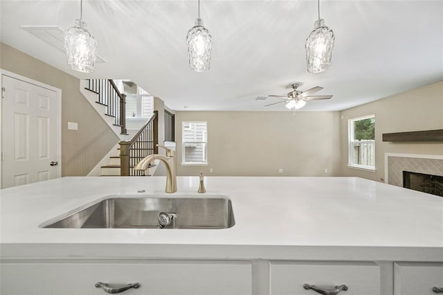 kitchen featuring sink, a fireplace, a wealth of natural light, and pendant lighting