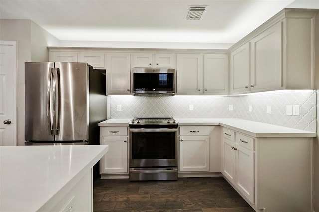 kitchen with tasteful backsplash, appliances with stainless steel finishes, and dark hardwood / wood-style flooring