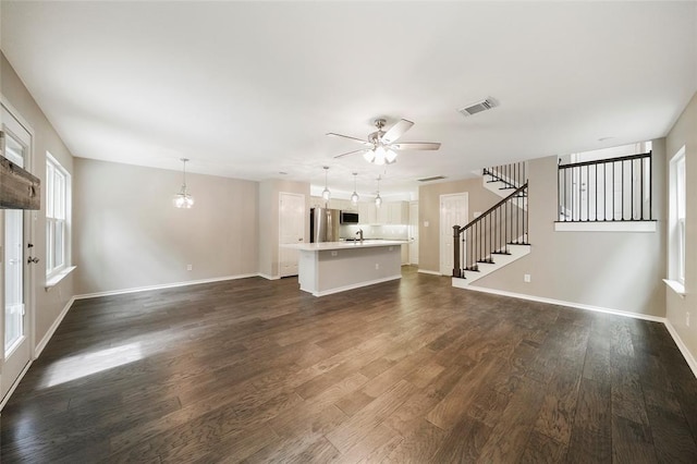 unfurnished living room with sink, ceiling fan, and dark wood-type flooring