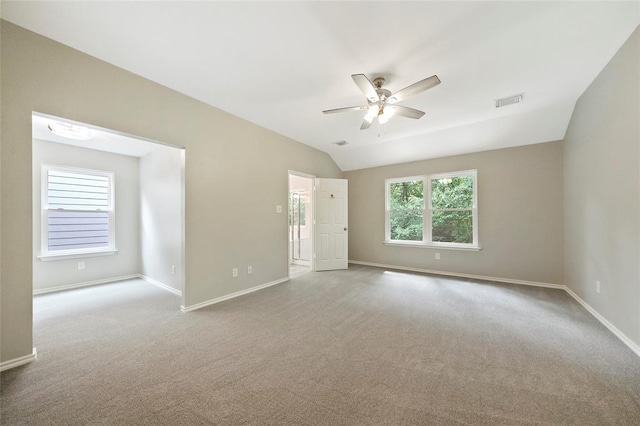 carpeted spare room featuring vaulted ceiling and ceiling fan