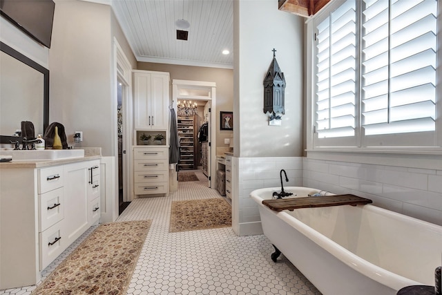 bathroom with a bathing tub, tile walls, ornamental molding, vanity, and tile patterned floors