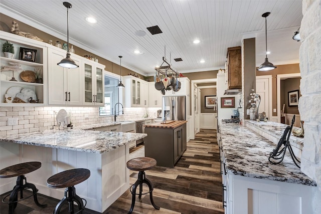 kitchen featuring appliances with stainless steel finishes, dark hardwood / wood-style floors, a center island, light stone counters, and white cabinets