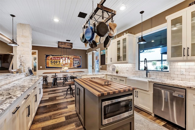 kitchen featuring stainless steel appliances, white cabinetry, hanging light fixtures, and sink