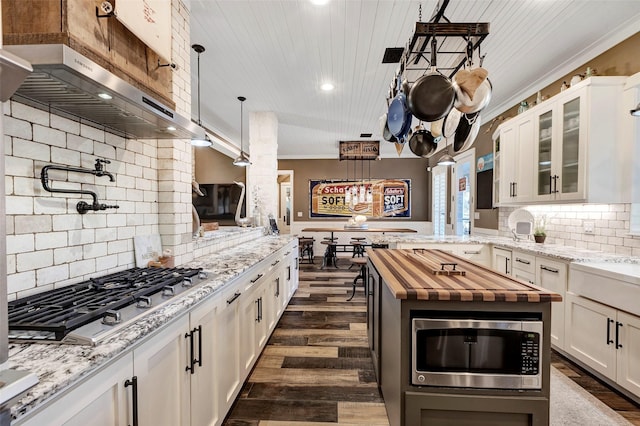 kitchen with pendant lighting, white cabinetry, backsplash, stainless steel appliances, and a center island