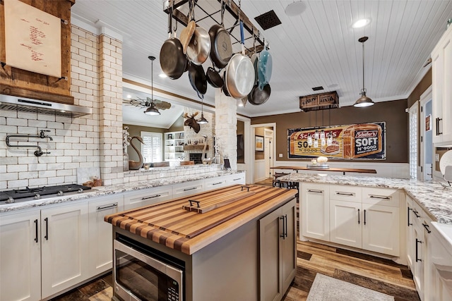 kitchen with tasteful backsplash, hanging light fixtures, white cabinets, and appliances with stainless steel finishes