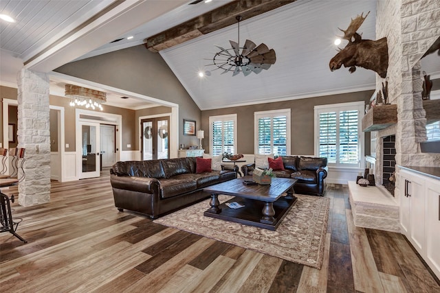 living room with crown molding, vaulted ceiling with beams, a fireplace, light hardwood / wood-style floors, and french doors