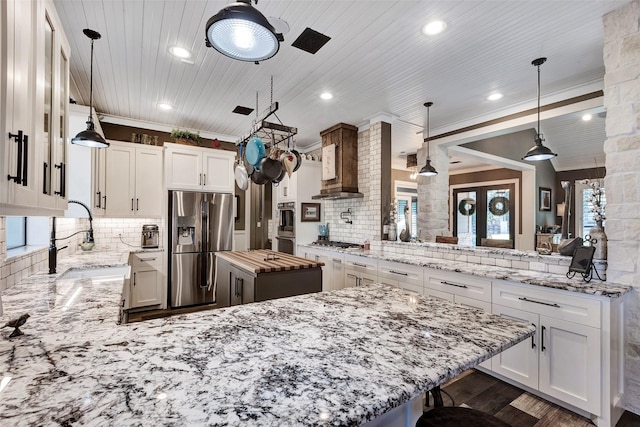 kitchen with decorative backsplash, appliances with stainless steel finishes, kitchen peninsula, and hanging light fixtures