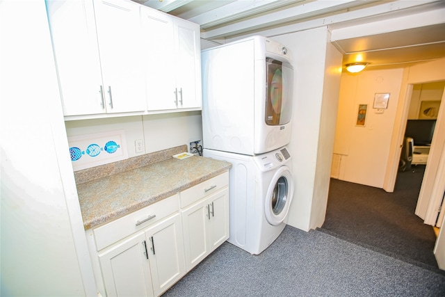 washroom with cabinets, dark colored carpet, and stacked washer and dryer