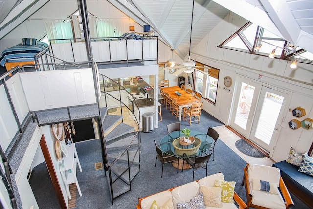 carpeted living room with ceiling fan, beamed ceiling, and high vaulted ceiling