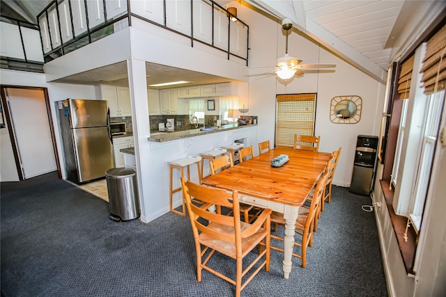 dining area featuring ceiling fan, sink, high vaulted ceiling, and light colored carpet